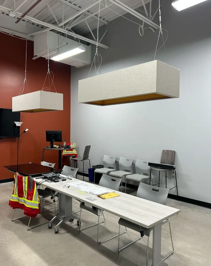 Suspended rectangular PET acoustic light fixtures in a meeting room